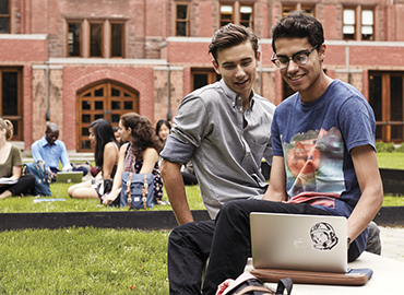 Two people are working together outdoor on computer