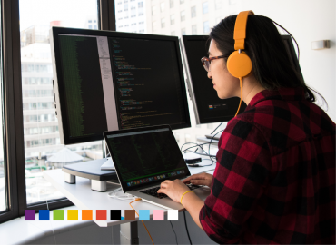 An entrepreneur on their computer working on their startup with a rainbow flag pattern displayed below.