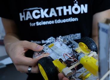 A team member holds the Robo-Dropper, a small robotic rover designed to drop seeds into the ground at regular intervals.